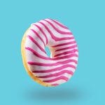 Pink glazed donut flying on blue background. Levitation concept food