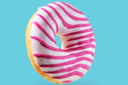 Pink glazed donut flying on blue background. Levitation concept food